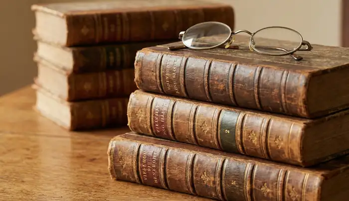 Stack of vintage antique books with reading glasses